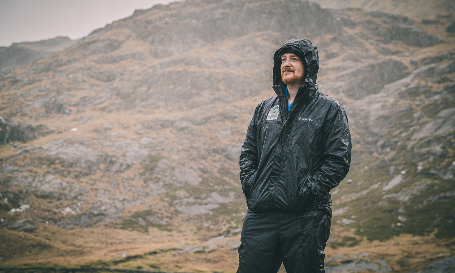 A warden looks over the foothills of Snowdon in heavy rain