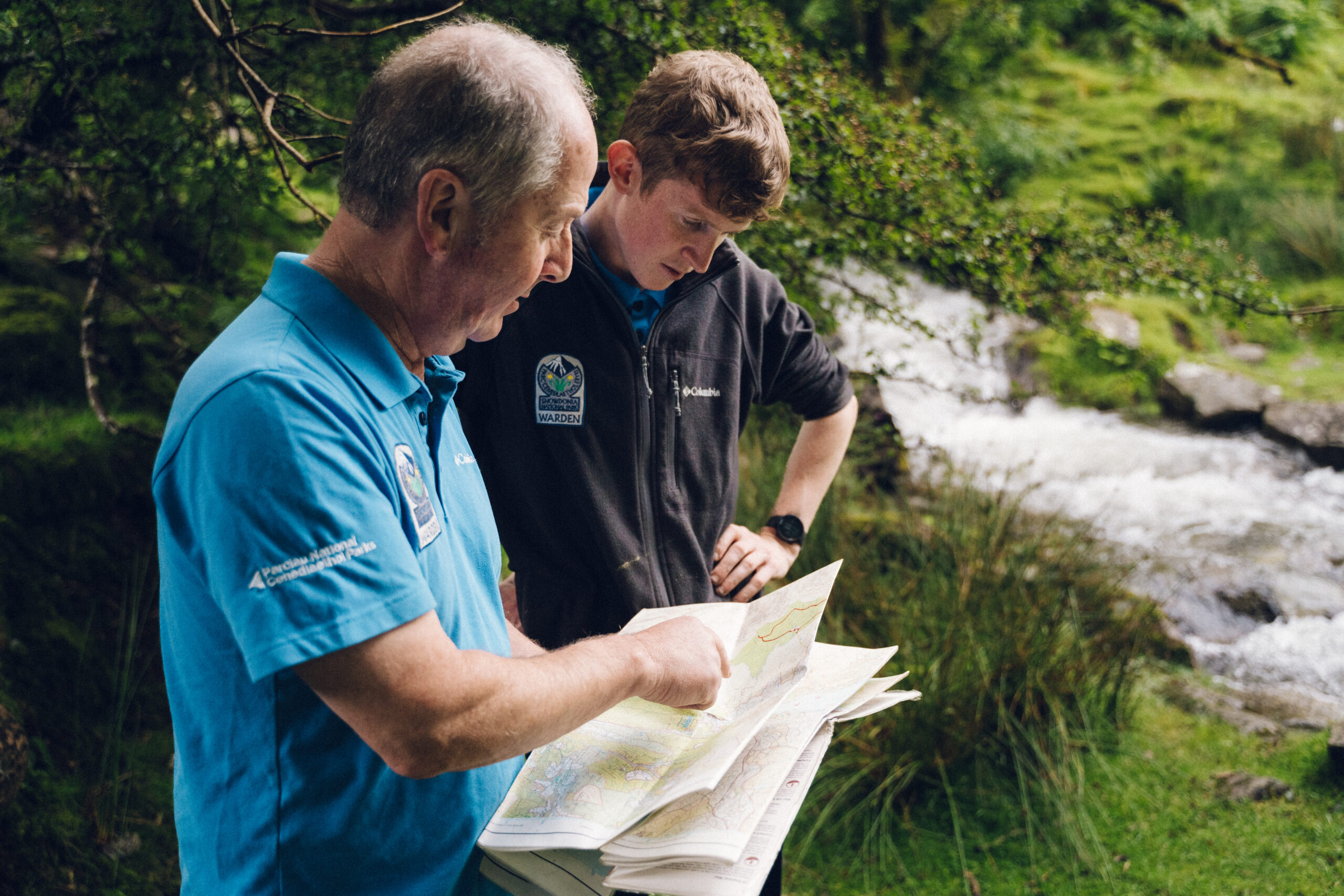 two wardens looking at a map, with one of them pointing to a specific area on the map