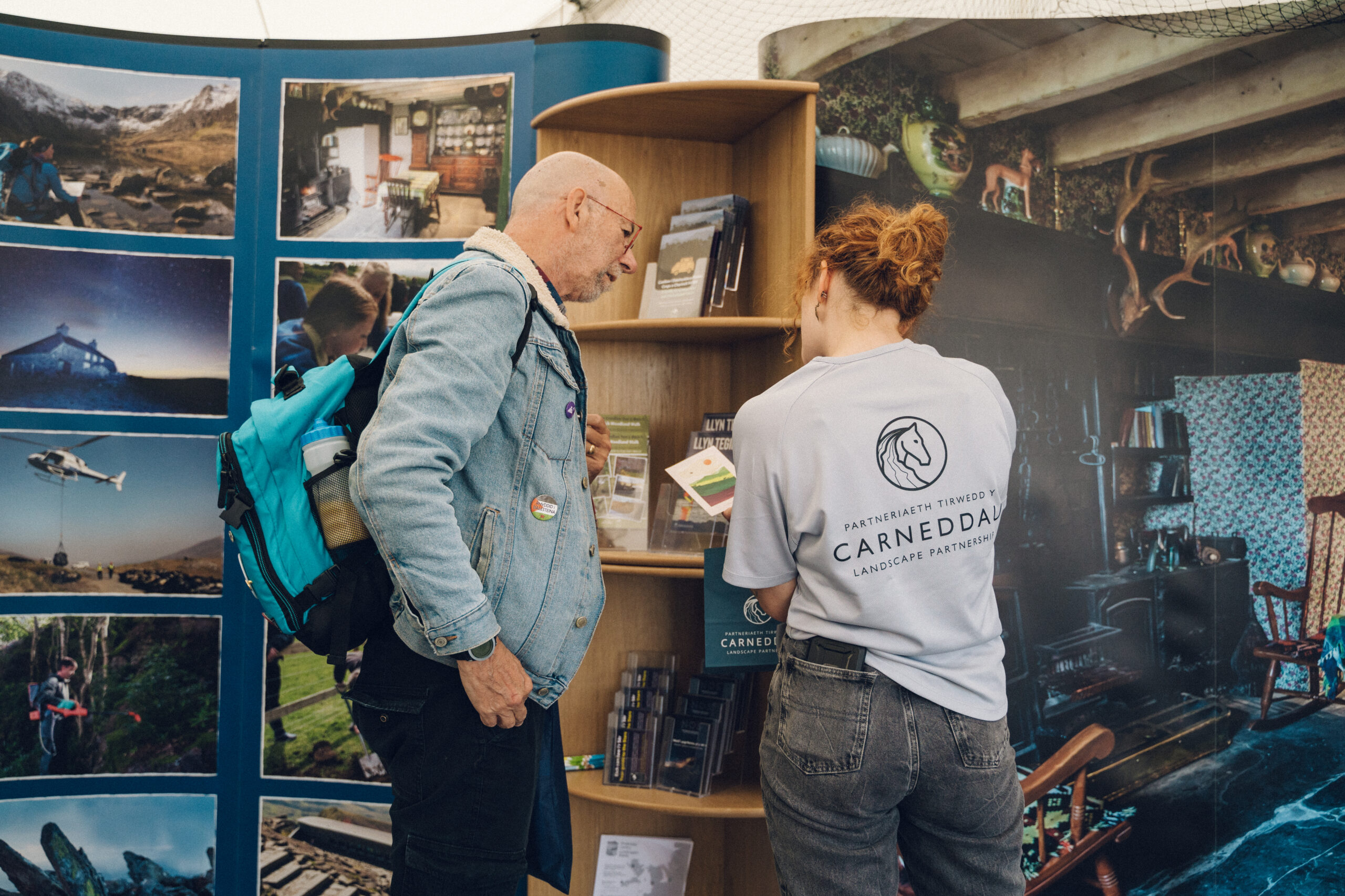 staff working at the Eisteddfod showing a member of the public an image of the carneddau mountains